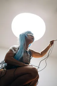 A futuristic person with blue hair and a silver visor entangled in wires, symbolizing the deep tech behind AI interaction.