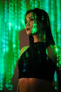 A woman's face illuminated by a projection of green, falling digital characters, symbolizing data collection.