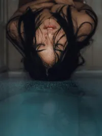 A woman's face reflected in water, symbolizing the deep emotional connection sought in AI companions.